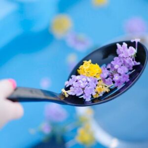 child scooping flowers out of a water sensory bin