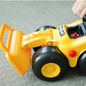 Child pushing yellow bulldozer toy construction vehicle