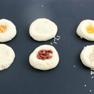 Play dough circles with different small objects like pasta, rice, oats, popcorn, and beans.