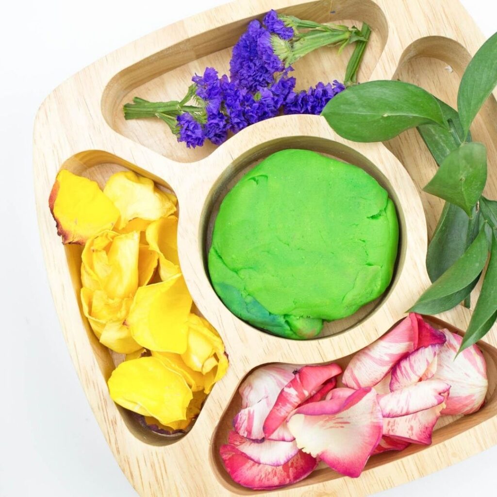 Spring theme preschool play dough activity. Tray with play dough, petals, flowers, and leaves.