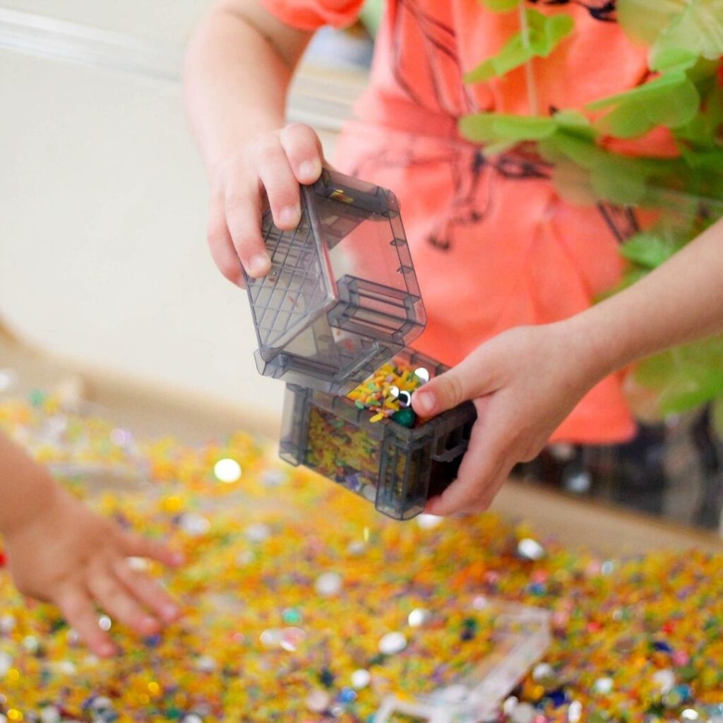 Summer preschool sensory bin with shimmery beads.