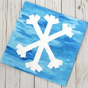 Tape resist snowflake preschool winter arts and crafts activity.