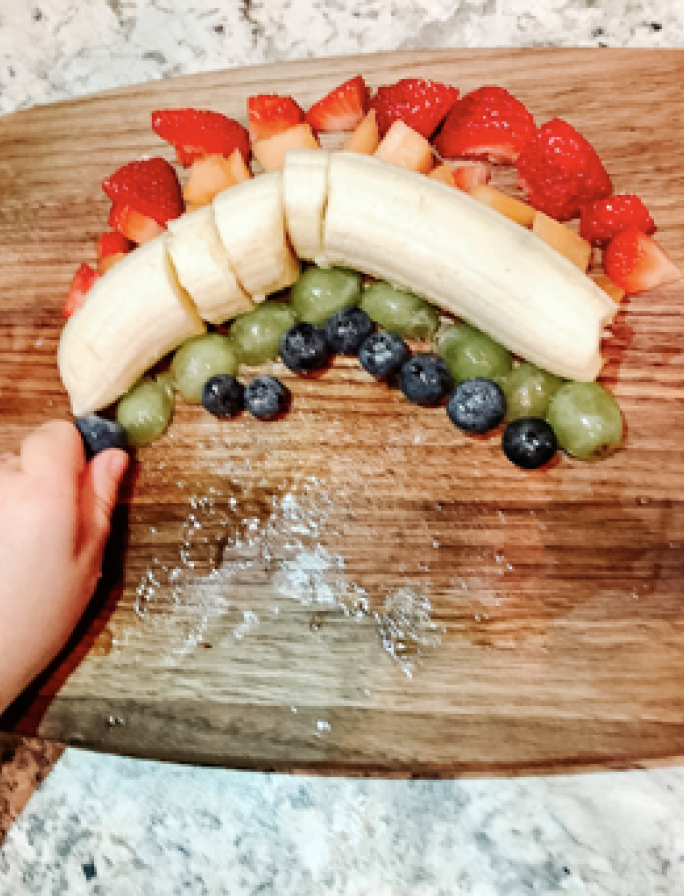 Fruit rainbow made with blueberries, grapes, banana and strawberries for preschool snack